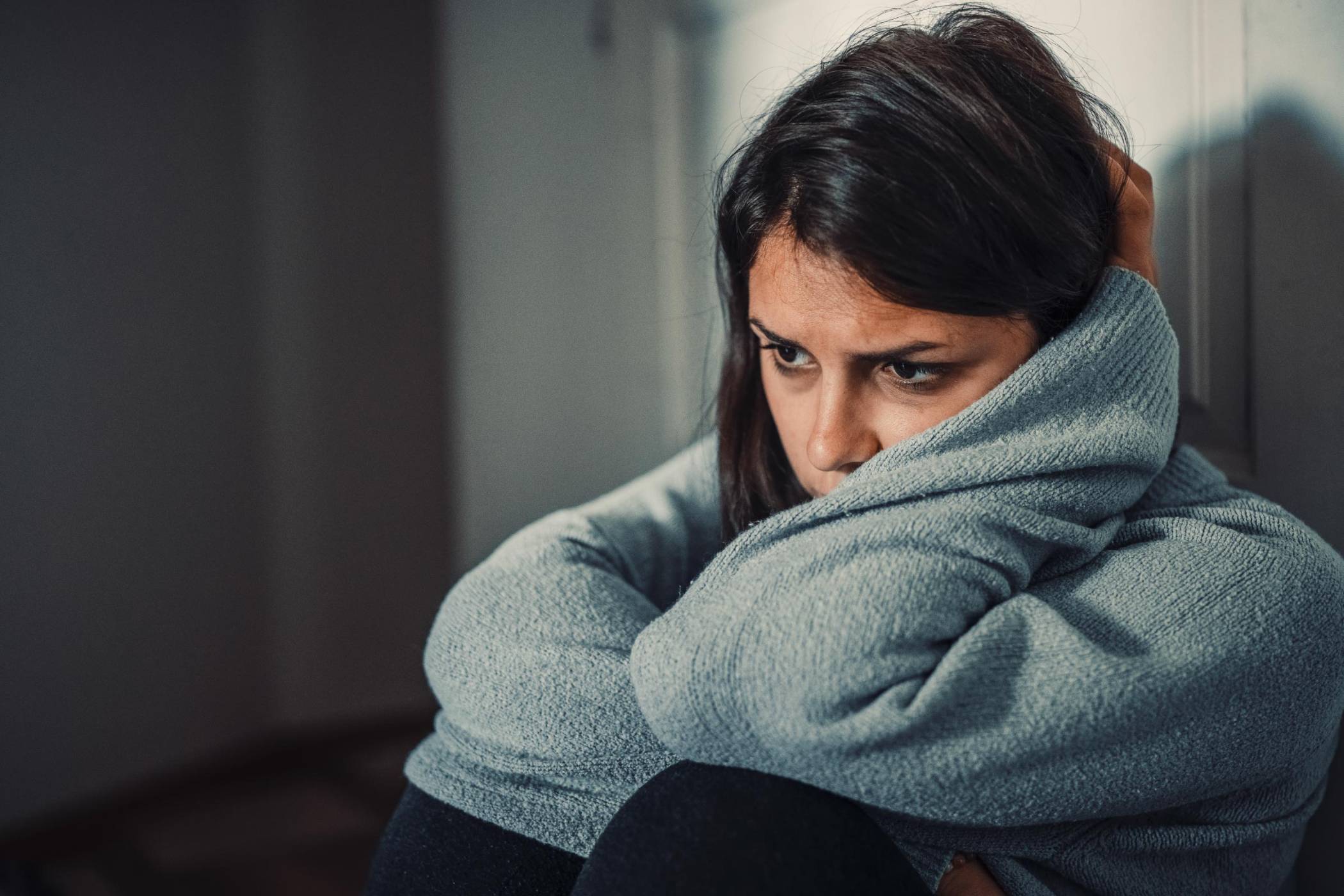 Woman sitting on the floor, looking down, worried like homeless children.