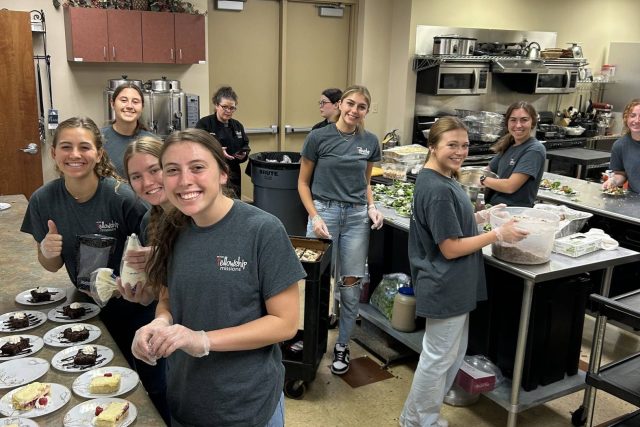 Group of people preparing food in a kitchen setting.