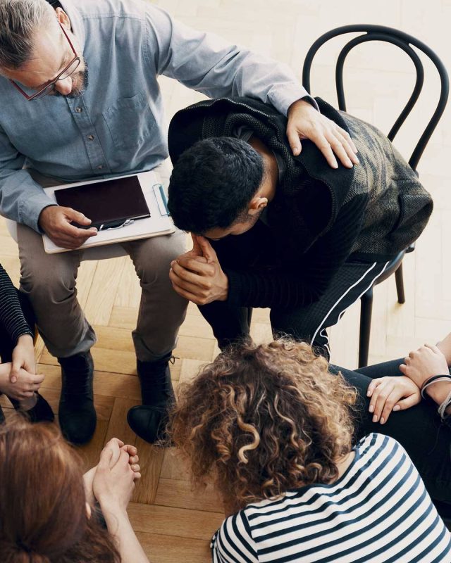 Group therapy session treating addiction with six in a supportive circle.
