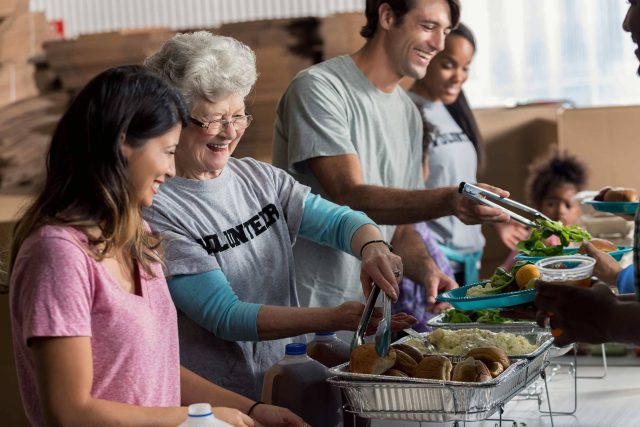 Volunteers supporting Fellowship Missions by serving food at a community event.