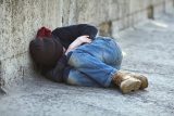 unhoused child sleeping curled up on the ground