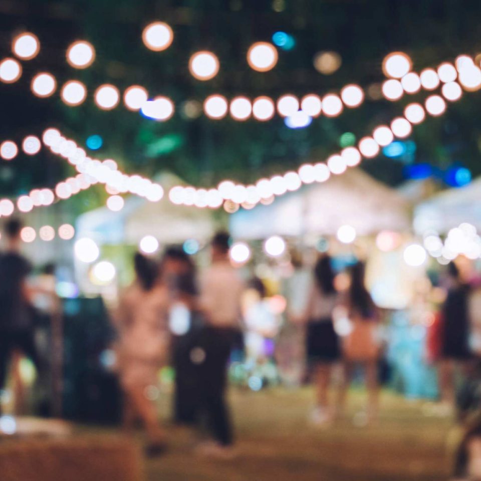 Blurred image of fellowship and string lights at an outdoor event.